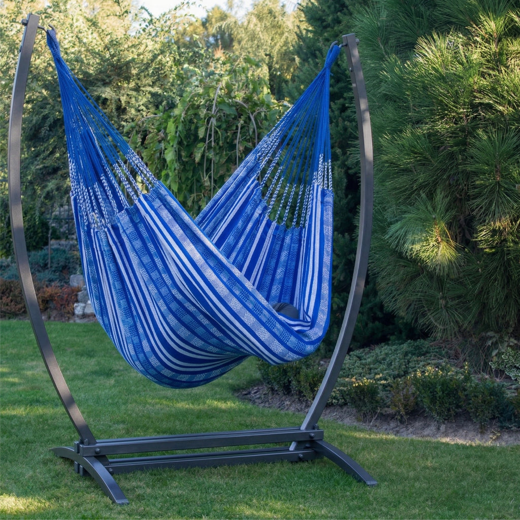 Hamac suspendu bleu de hamacio dans un jardin avec une personne assise au milieu 