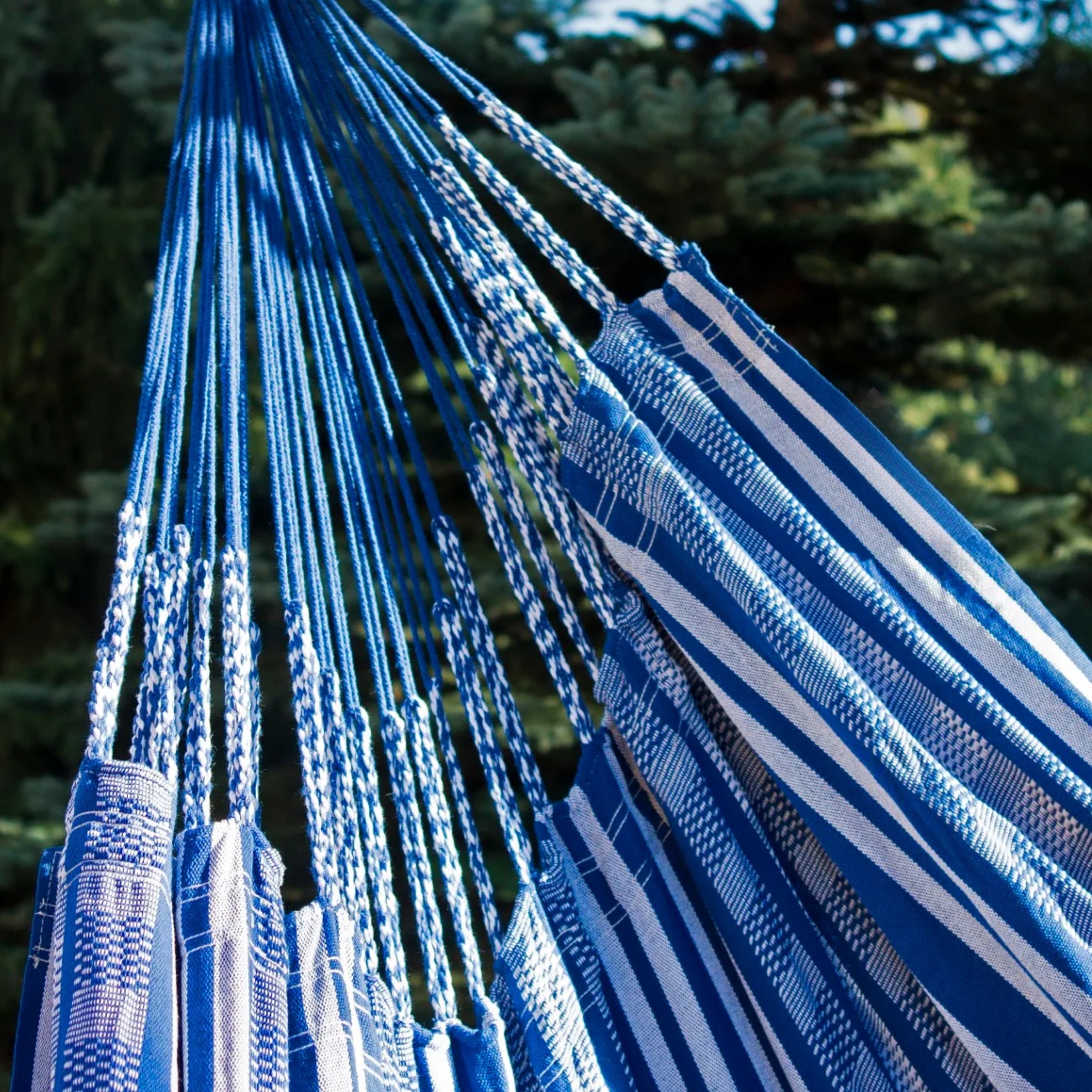 Hamac suspendu bleu de hamacio dans un jardin avec un zoom sur la matière et le tissu