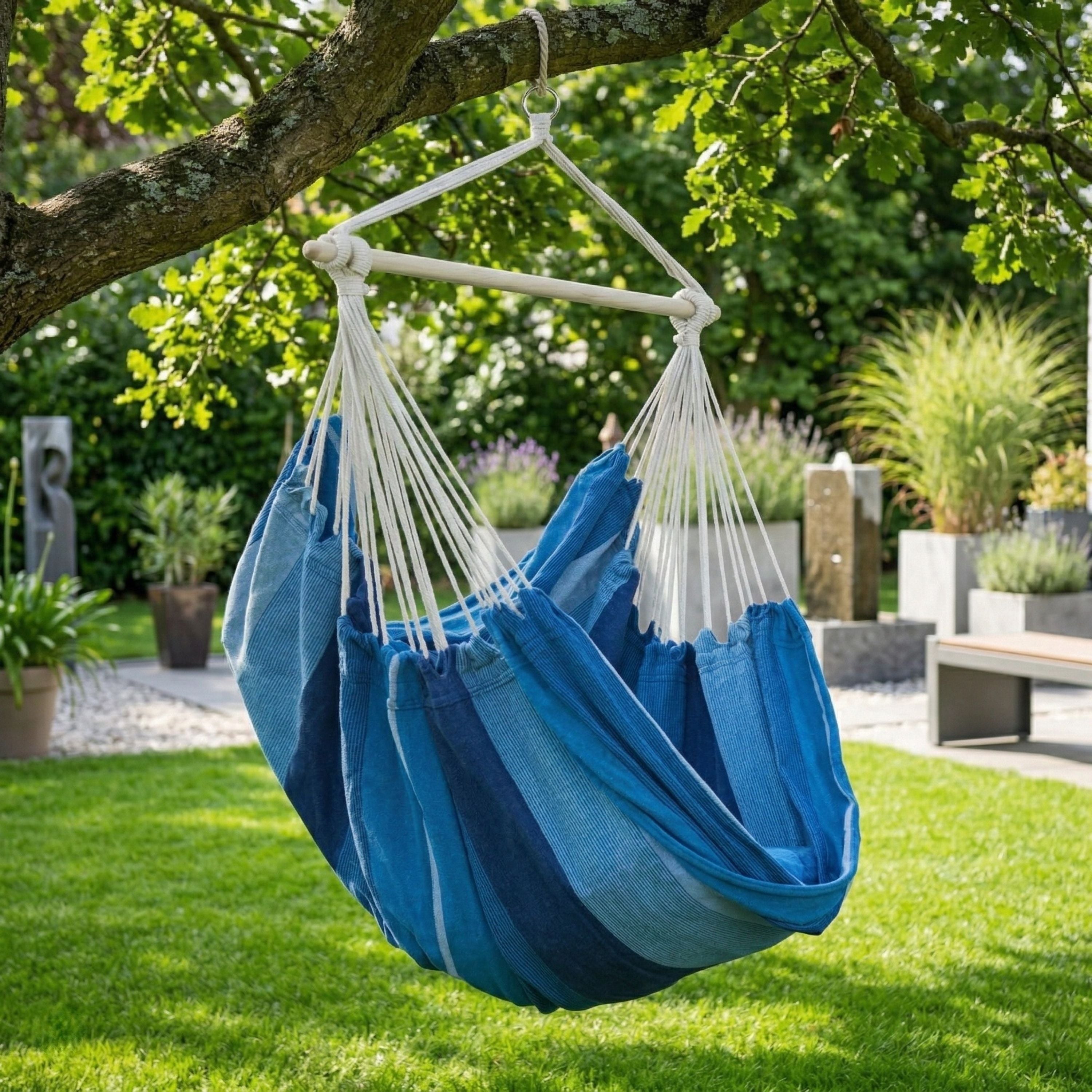 Fauteuil suspendu bleu Horizonte de chez Hamacio dans un jardin moderne et lumineux 