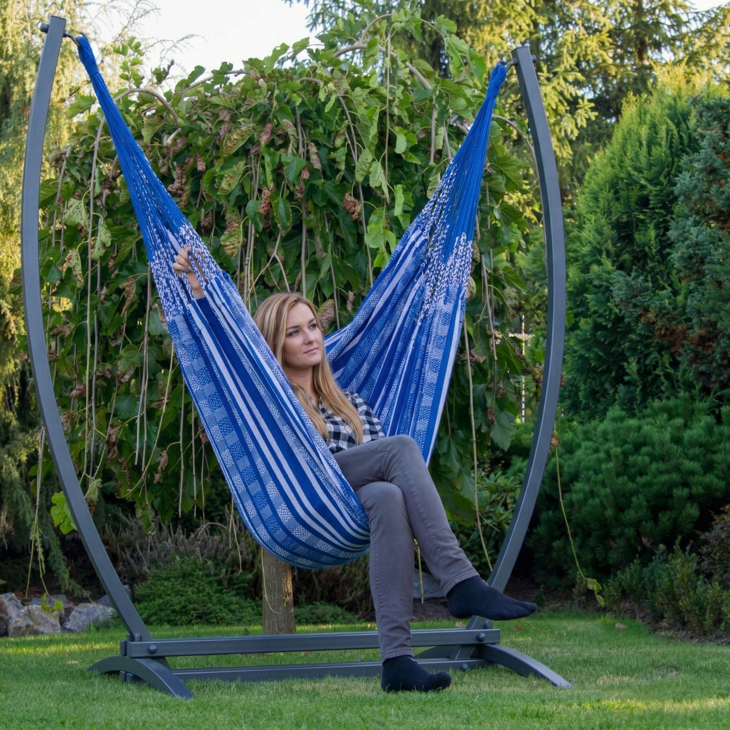 Hamac suspendu bleu de hamacio dans un jardin avec une femme assise confortablement 