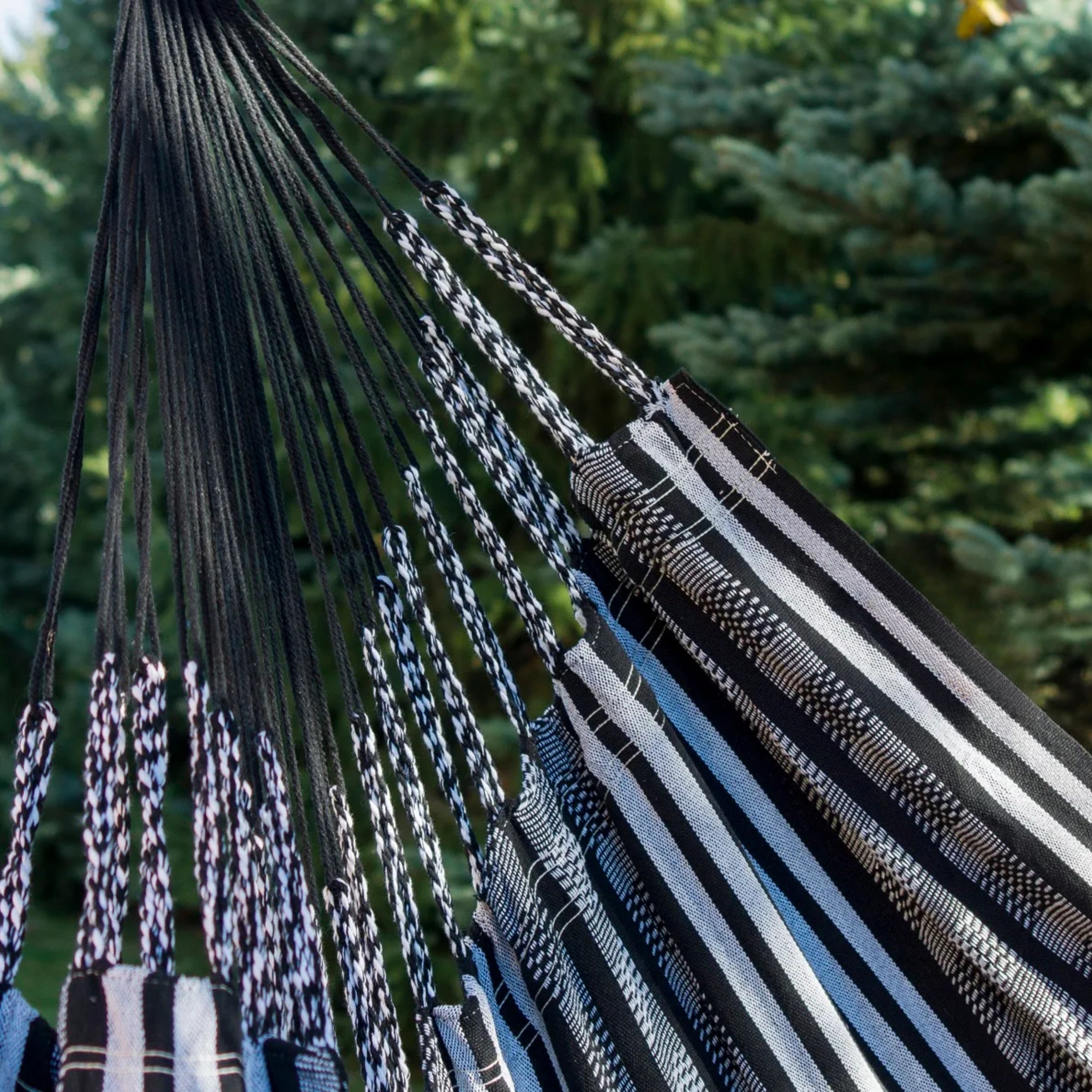 Hamac suspendu noir de hamacio dans un jardin avec un zoom sur le tissu