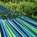 Hamac vert et bleu horizonte, dans un jardin lumineux.