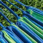 Hamac vert et bleu horizonte, zoom sur le hamac et les cordes dans un jardin.