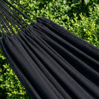 zoom sur le hamac noir de la collection suave de hamacio dans un jardin de maison