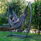 Hamac suspendu noir de hamacio dans un jardin avec une femme assise en train de lire un livre 