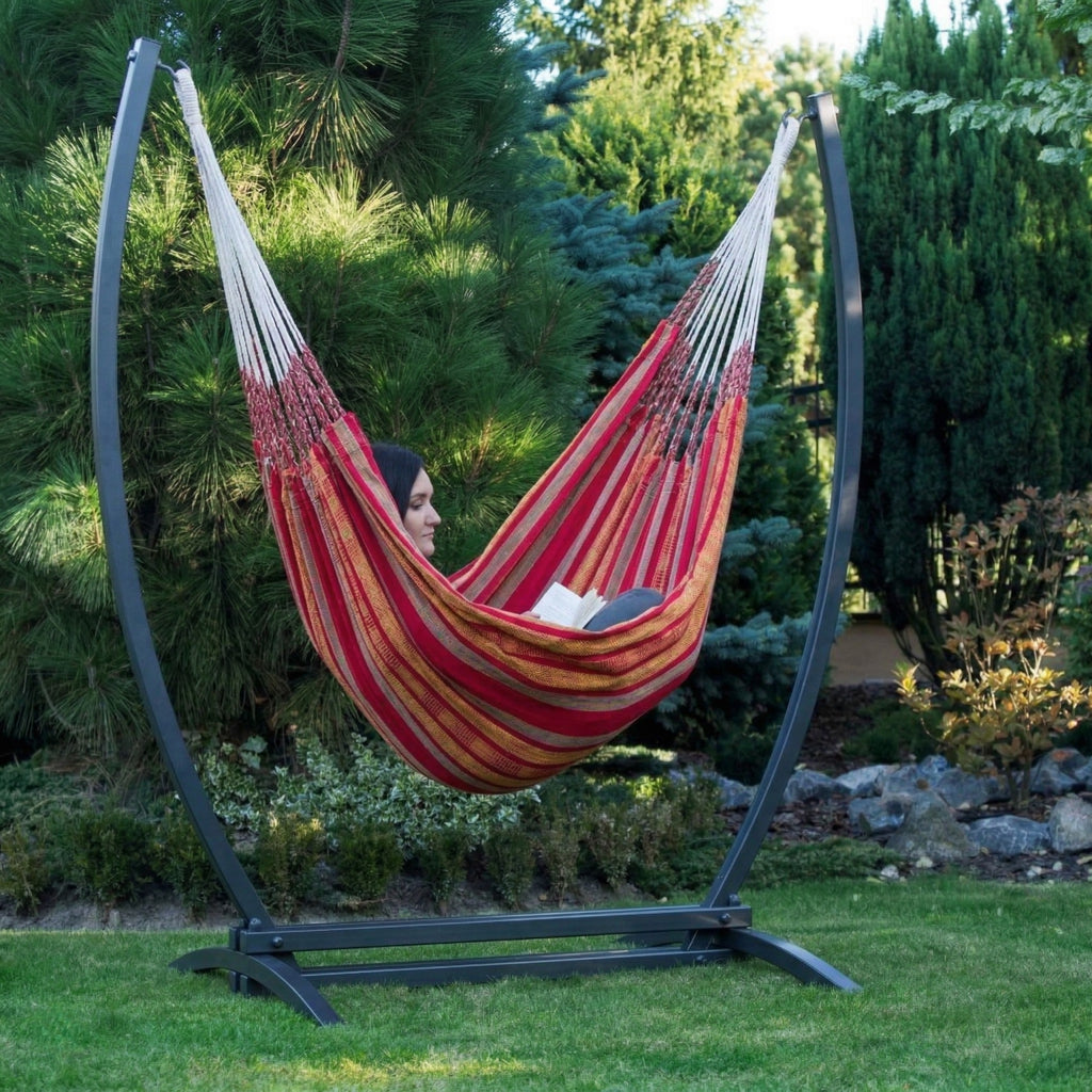 Grand hamac suspendu orange de hamacio dans un jardin avec une femme assise confortablement 