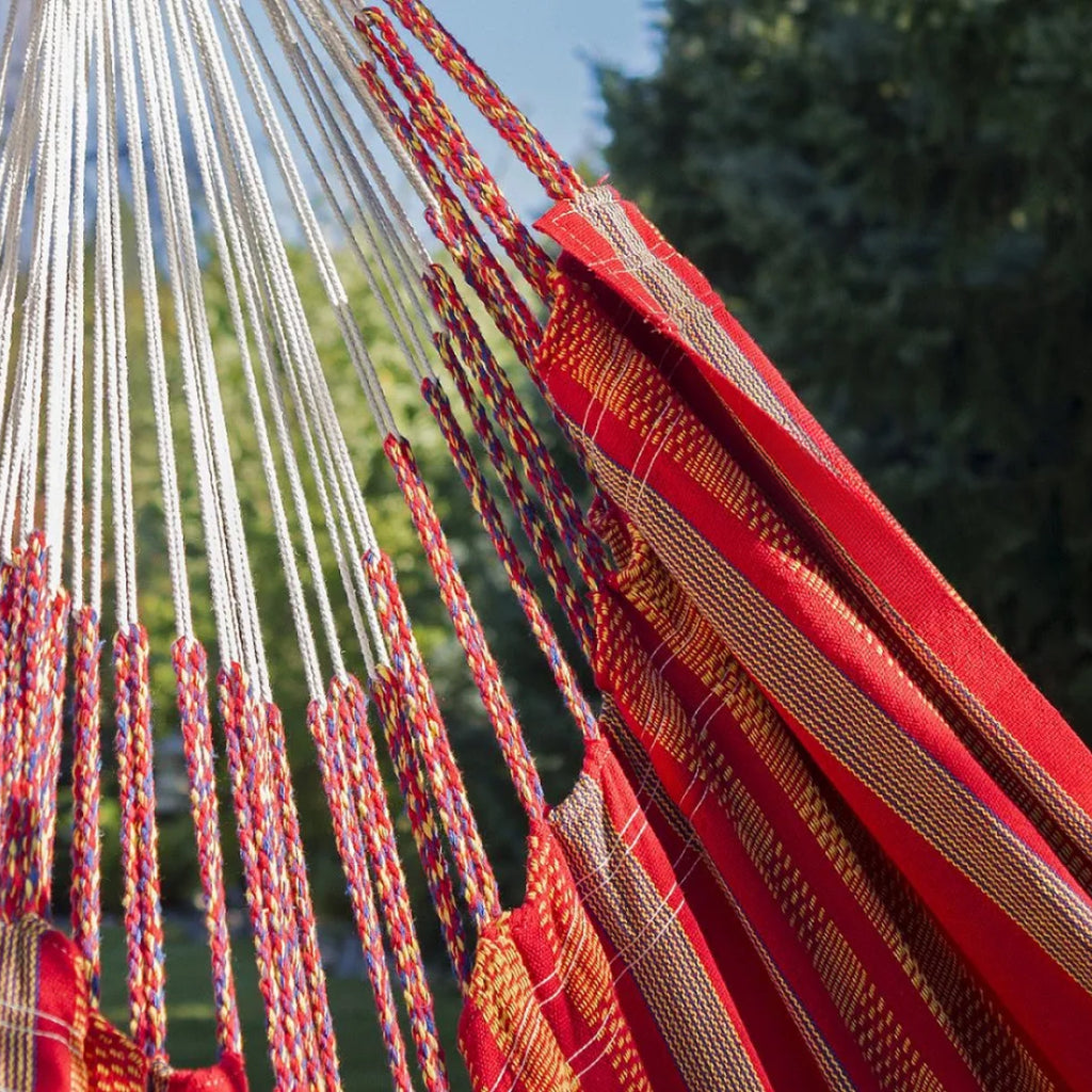 Hamac suspendu orange de hamacio dans un jardin avec un zoom sur le tissu